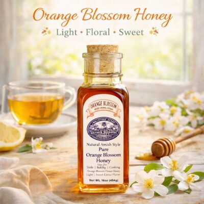 Pure Orange Blossom Honey bottle displayed with fresh citrus, orange blossoms, honey dipper, and bright farmhouse kitchen styling.