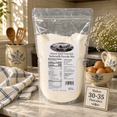 Millstone Acres Buttermilk Pancake Mix package displayed in a bright farmhouse kitchen with eggs and baking ingredients.
